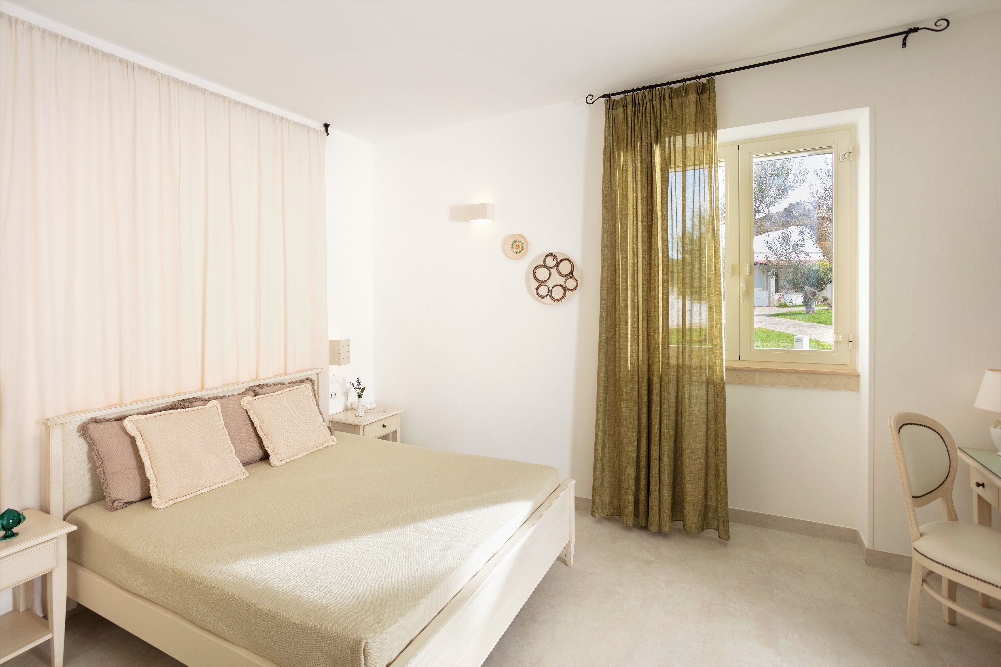 Une chambre à coucher avec un lit, une table de chevet, une chaise et une fenêtre avec des rideaux.