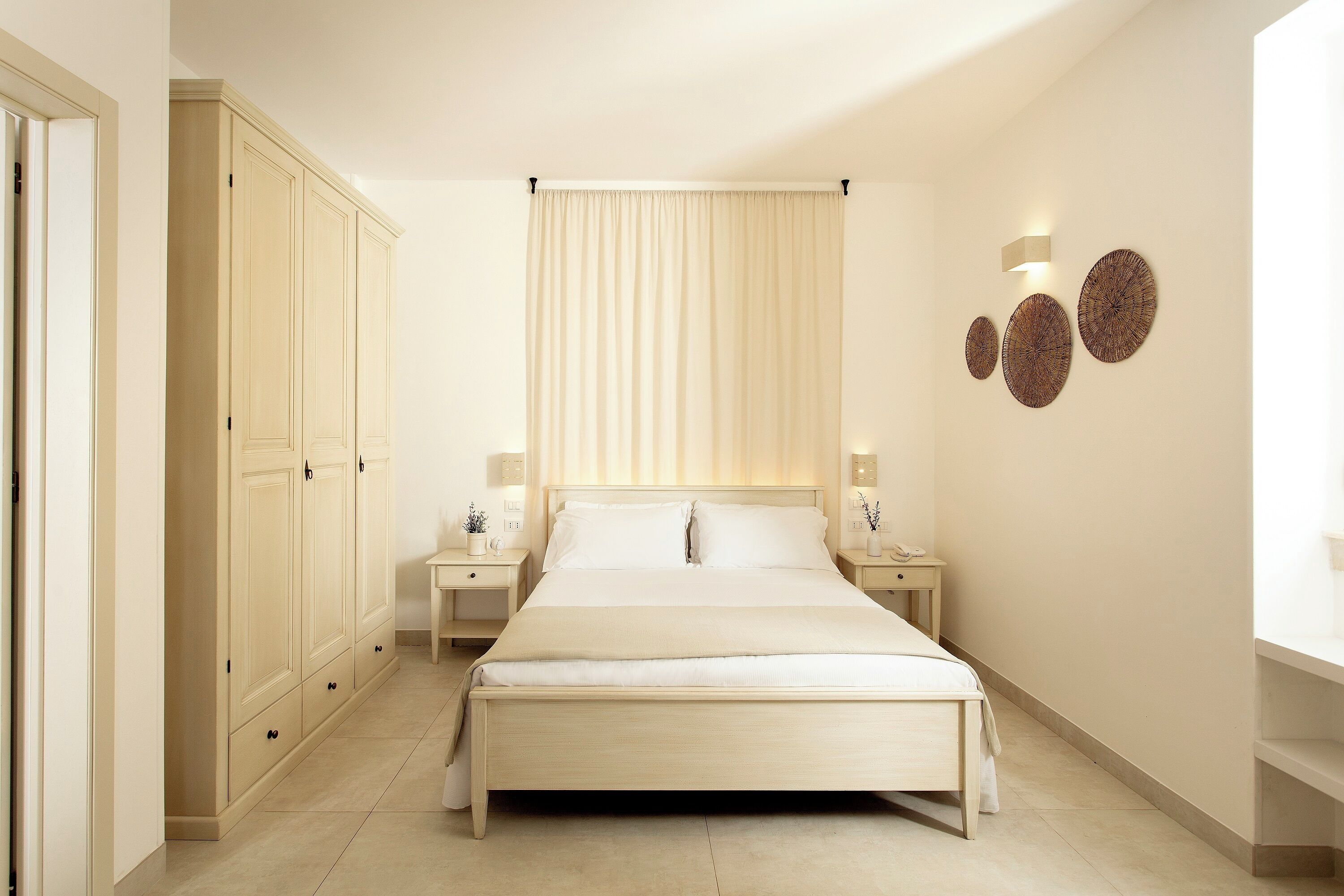 Un dormitorio con una cama grande, un armario, mesitas de noche y elementos decorativos en la pared.