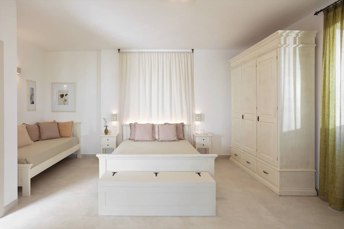A bedroom with a bed, bedside tables, a wardrobe, and a bench.