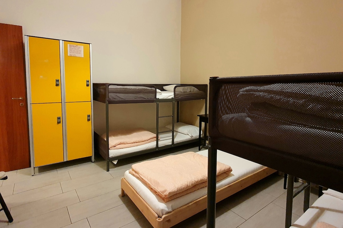 Un dormitorio con literas, un armario amarillo y un escritorio.