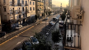 Une vue de rue avec des immeubles à plusieurs étages, des voitures garées et un passage piéton.