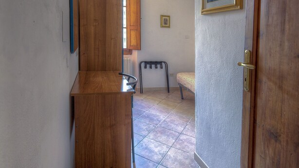 Un pasillo con un banco de madera, una puerta y un cuadro enmarcado en la pared.