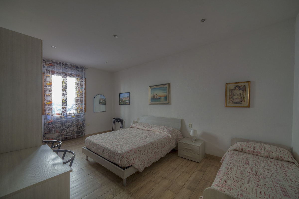 A bedroom with a bed, bedside table, and a chair.
