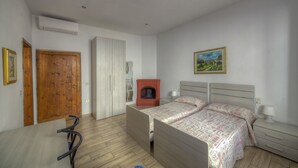 Un dormitorio con cama, mesita de noche, lámpara y un cuadro en la pared.