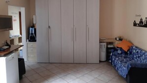 Una habitación con armario, escritorio, silla, cama y un adorno en la pared.
