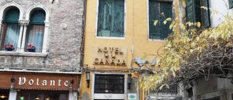 A hotel named "HOTEL CANADA" with a yellow facade, arched windows, and a visible entrance.