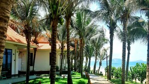 A pathway lined with palm trees leading to a building with a tiled roof. - Saigon Emerald Resort (Mui Ne)