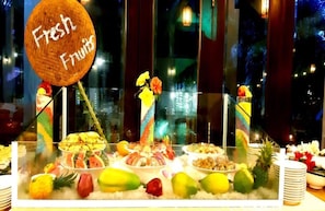 A buffet with a variety of fruits and dishes, including a sign that reads "Fresh Fruits".