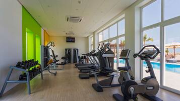 A gym with treadmills, elliptical machines, and a rack of dumbbells.