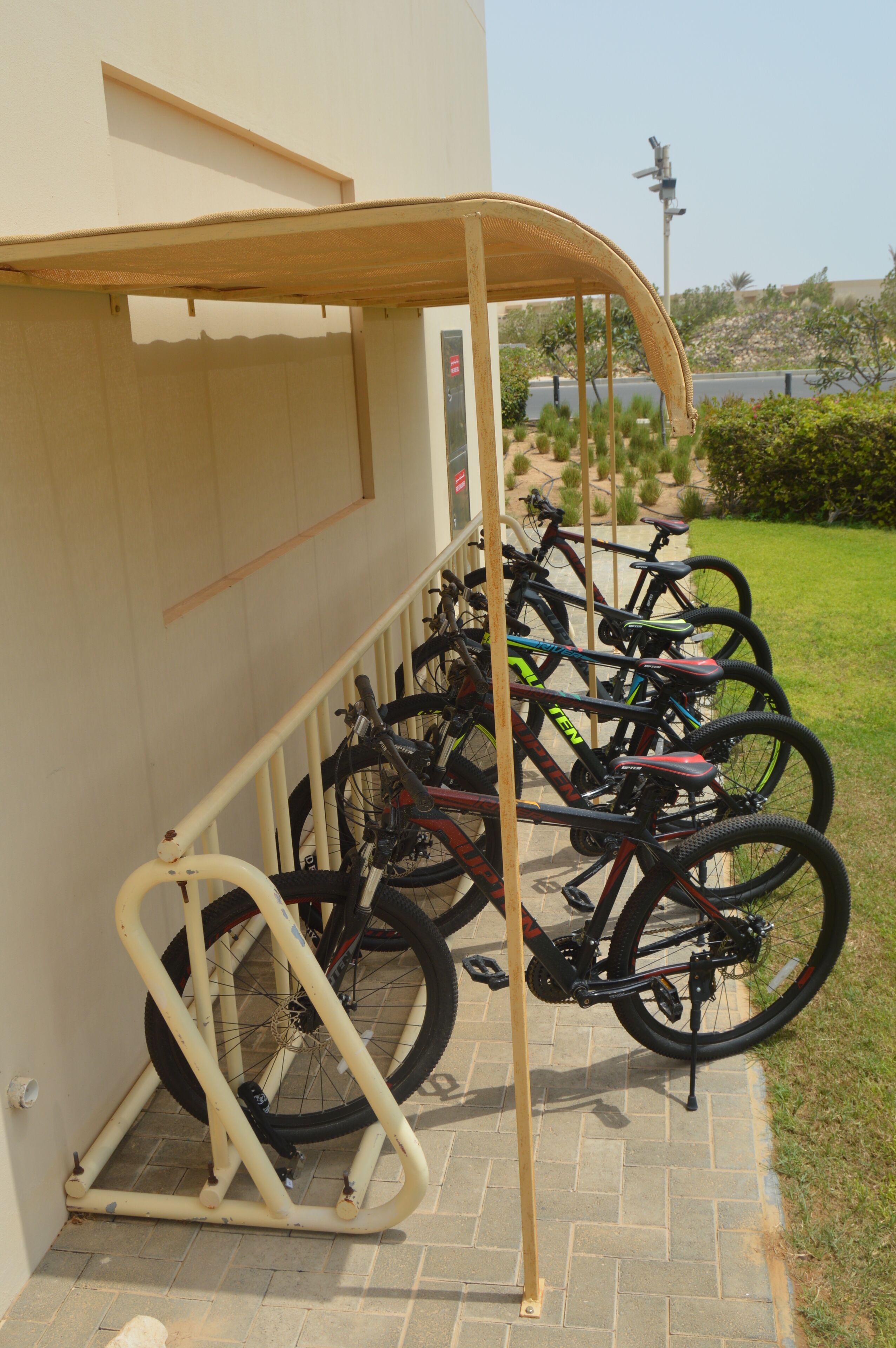 Un aparcaciclos con varias bicicletas estacionadas junto a una pared de edificio.