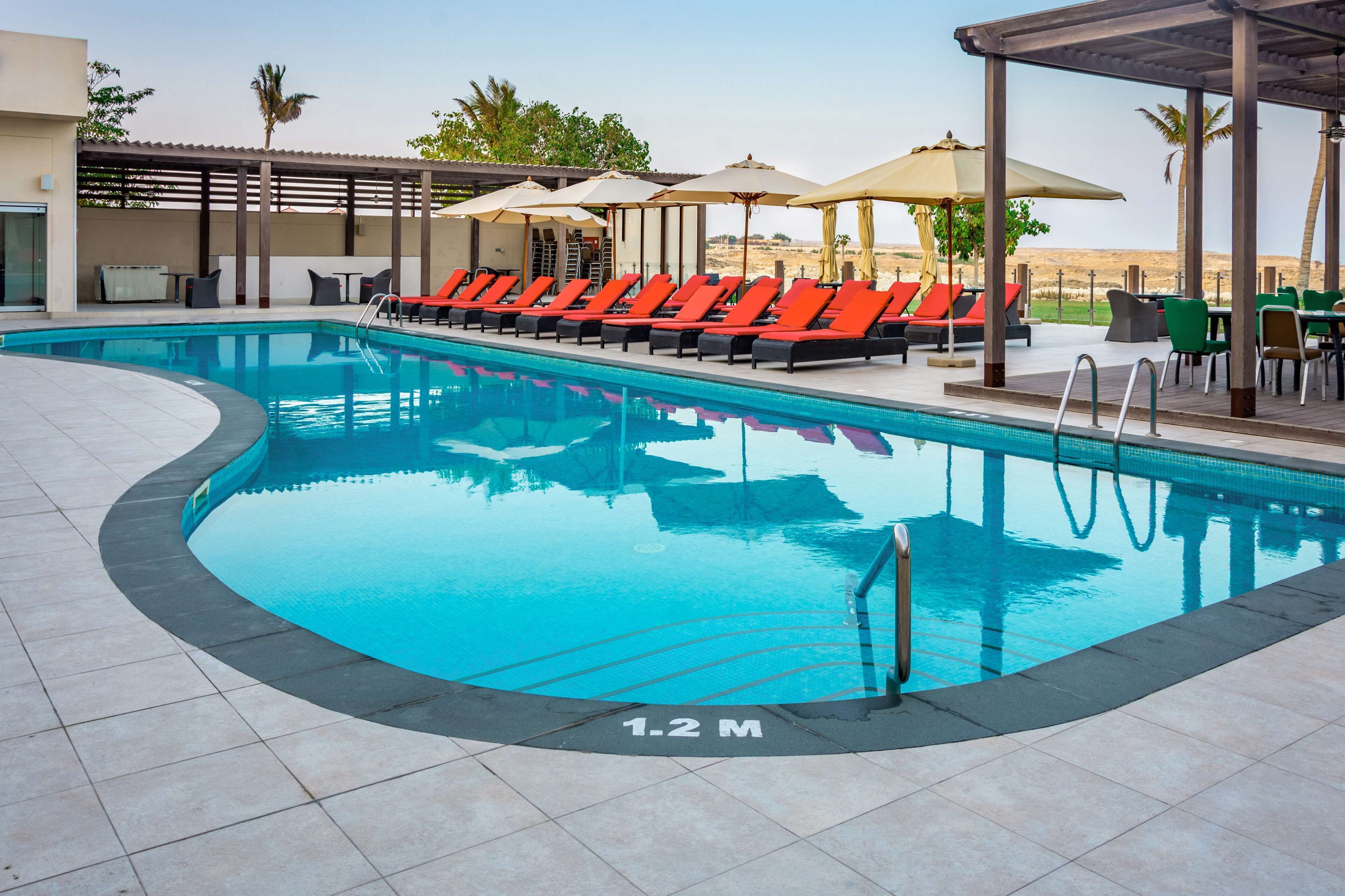 A swimming pool with lounge chairs and umbrellas, surrounded by a covered patio area.