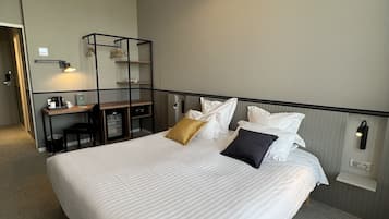 A neatly arranged hotel room with a large bed, bedside tables, a desk, and a hanging light fixture.