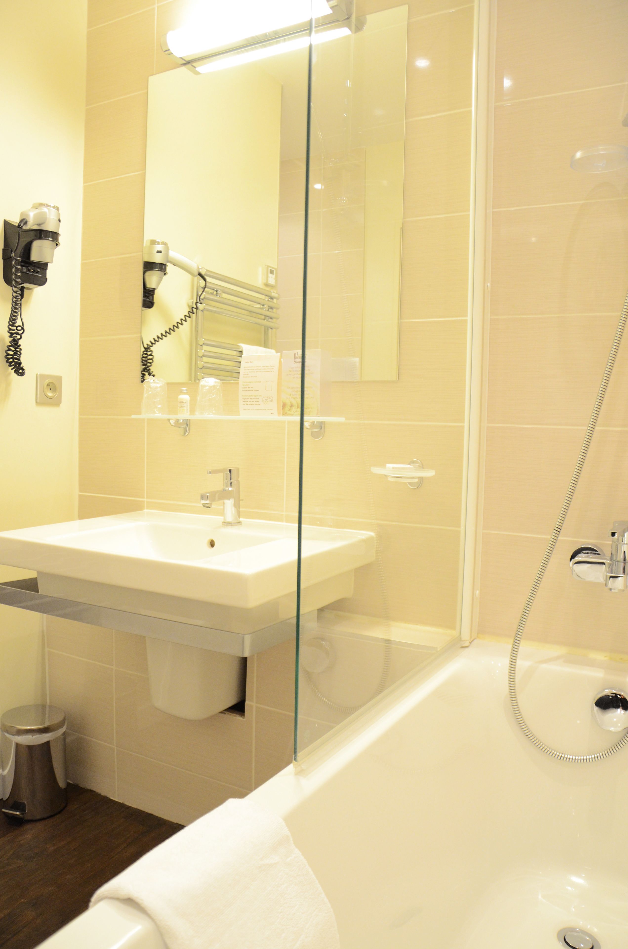 Un baño con cabina de ducha de vidrio, un lavabo y un secador de pelo montado en la pared.