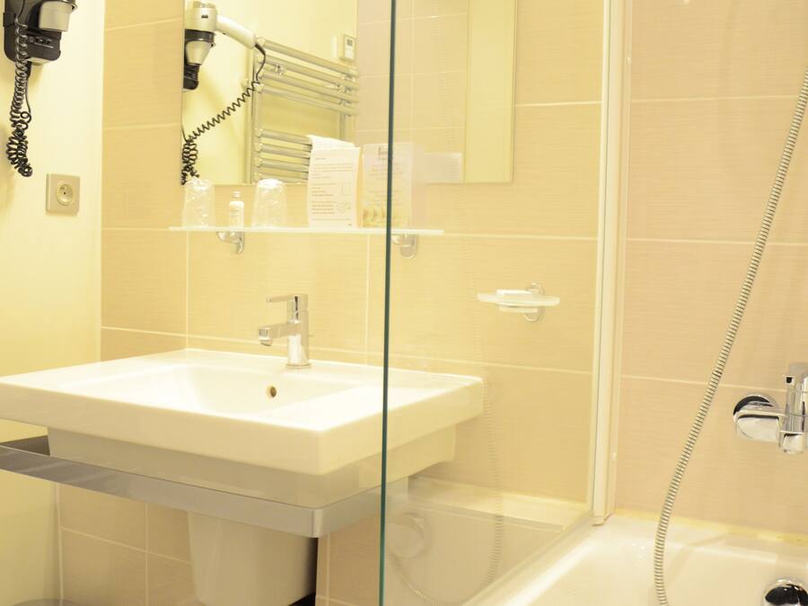 Un baño con cabina de ducha de vidrio, un lavabo y un secador de pelo montado en la pared.