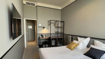Une chambre d’hôtel avec un grand lit, un bureau et une chaise. Il y a un téléviseur fixé au mur et une armoire.