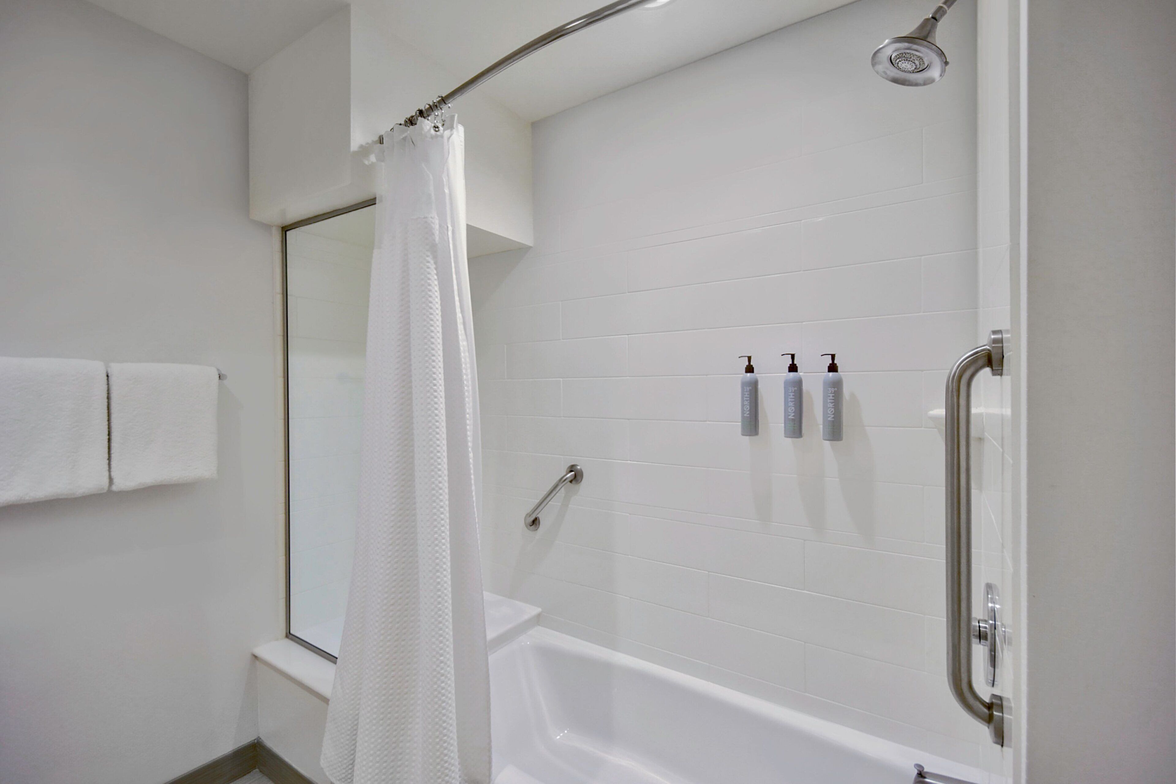 A modern bathroom with a white bathtub, a shower with a handheld showerhead, and a glass-enclosed shower stall.
