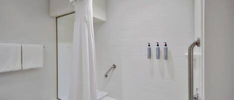 A modern bathroom with a white bathtub, a shower with a handheld showerhead, and a glass-enclosed shower stall.