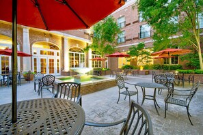 Un patio al aire libre con paredes de ladrillo, asientos exteriores y una fuente central.