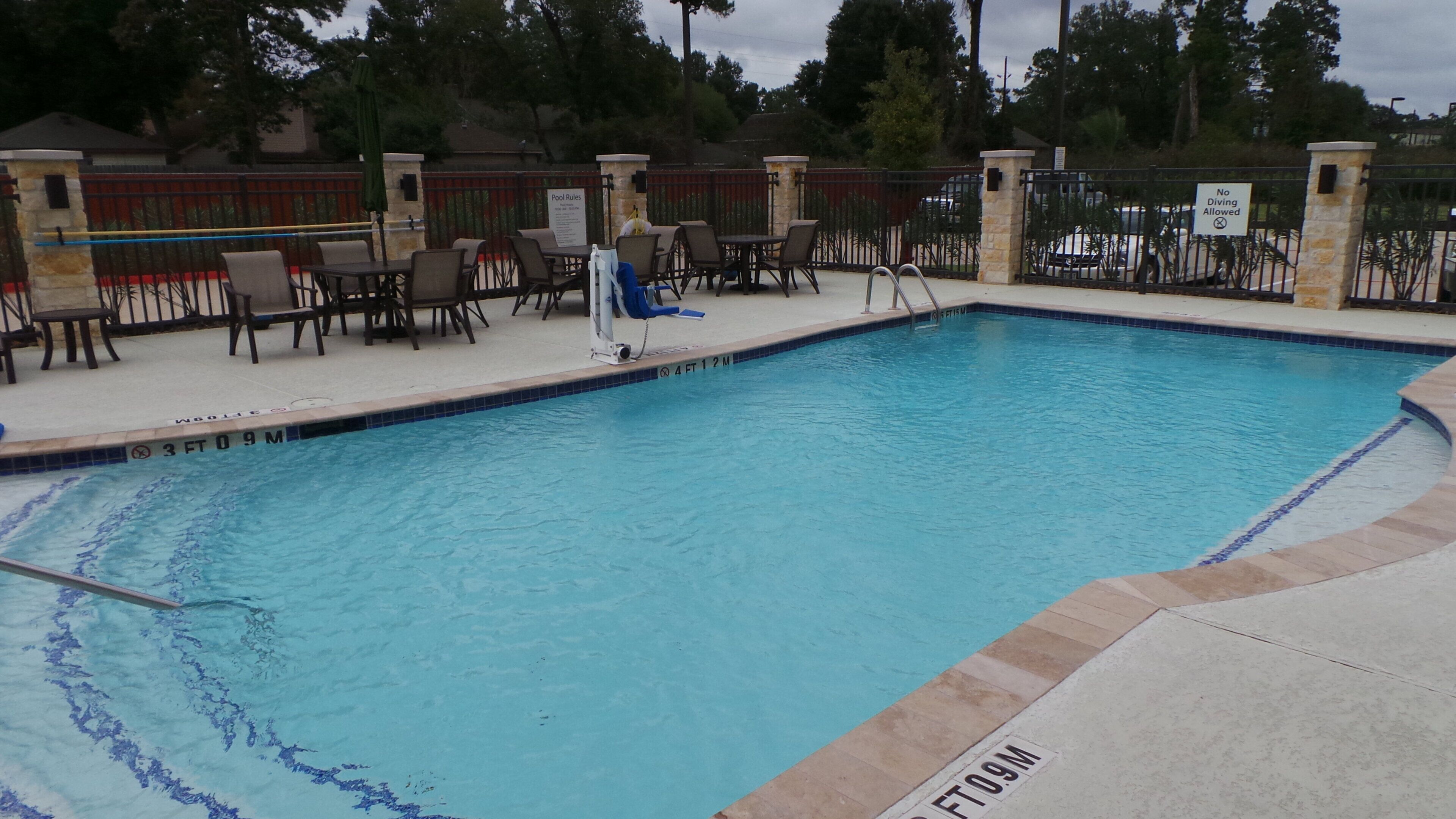 A swimming pool with lounge chairs and a sign indicating no diving allowed.