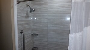 Ducha con cabezal de ducha de mano, barra de apoyo, estante pequeño y cortina de baño.