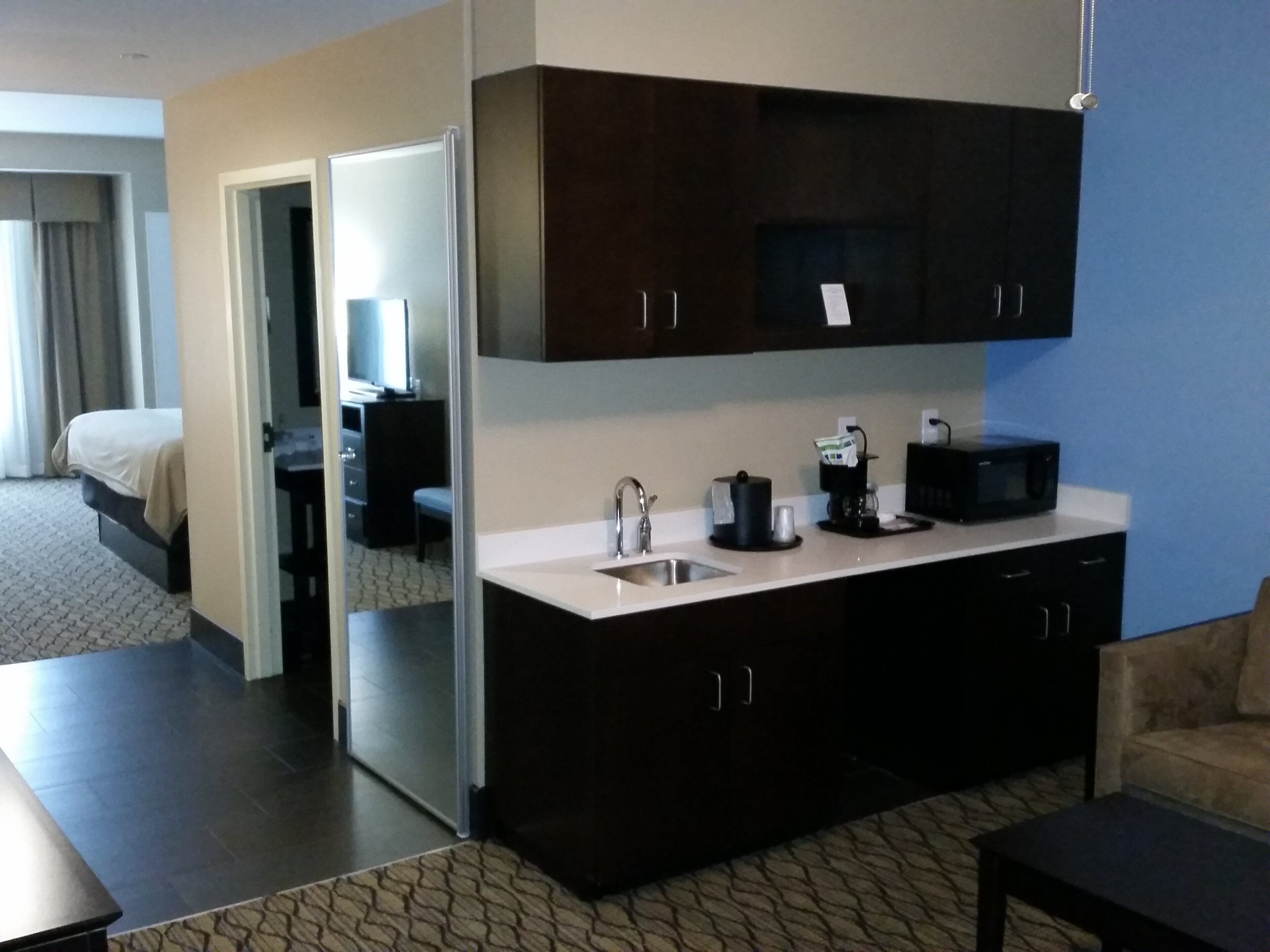 Habitación de hotel con kitchenette, una cama, un escritorio y una silla.