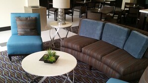 A hotel lobby with a blue sofa, a brown sofa, and a round table with a plant. - Holiday Inn Express & Suites Atascocita - Humble - Kingwood by IHG (Humble)