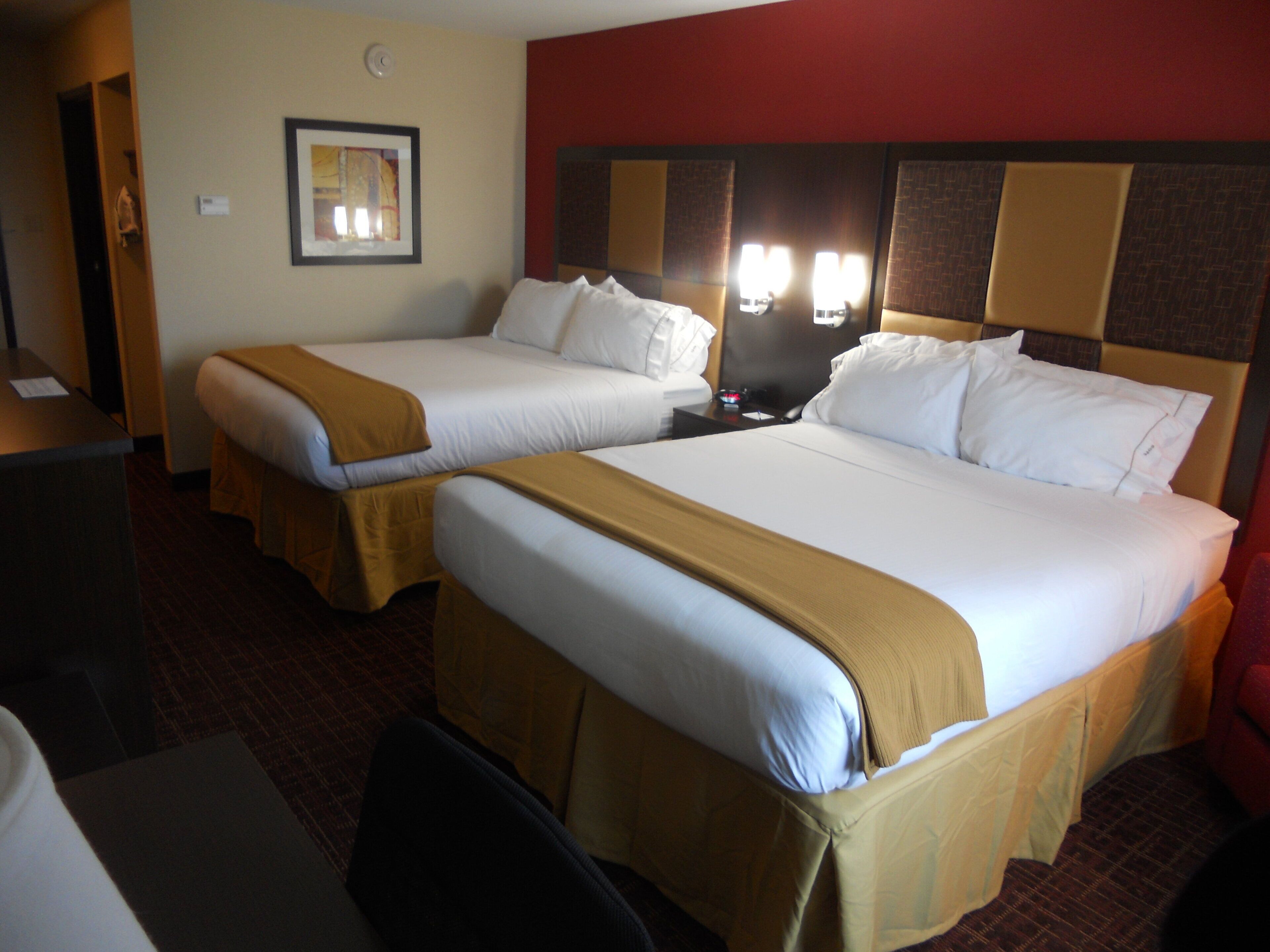 A hotel room with two beds, a desk, and a chair.