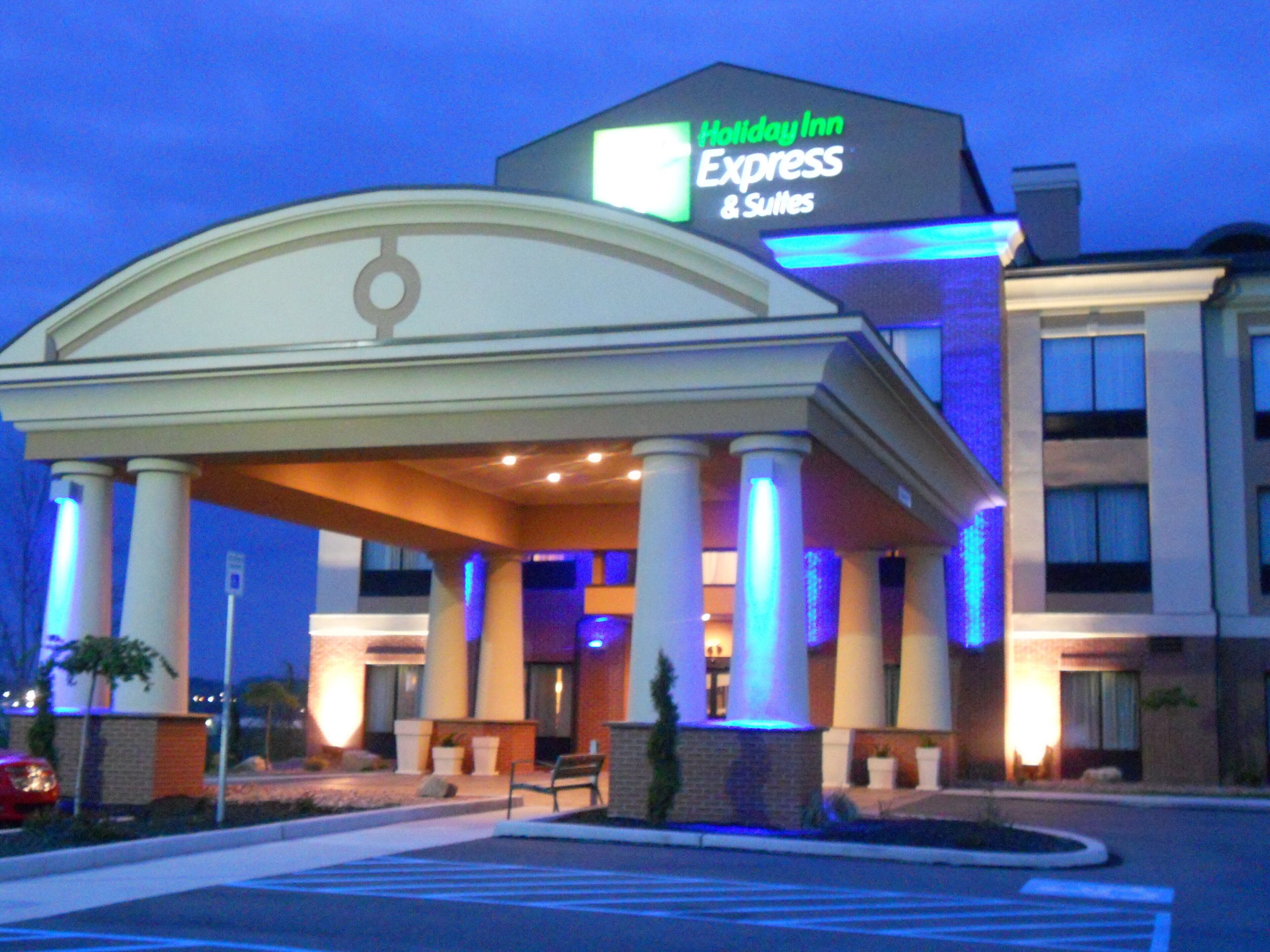 A Holiday Inn Express & Suites building with a covered entrance, columns, and a sign.