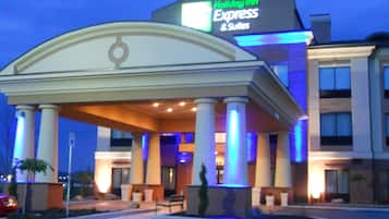 A Holiday Inn Express & Suites building with a covered entrance, columns, and a sign.