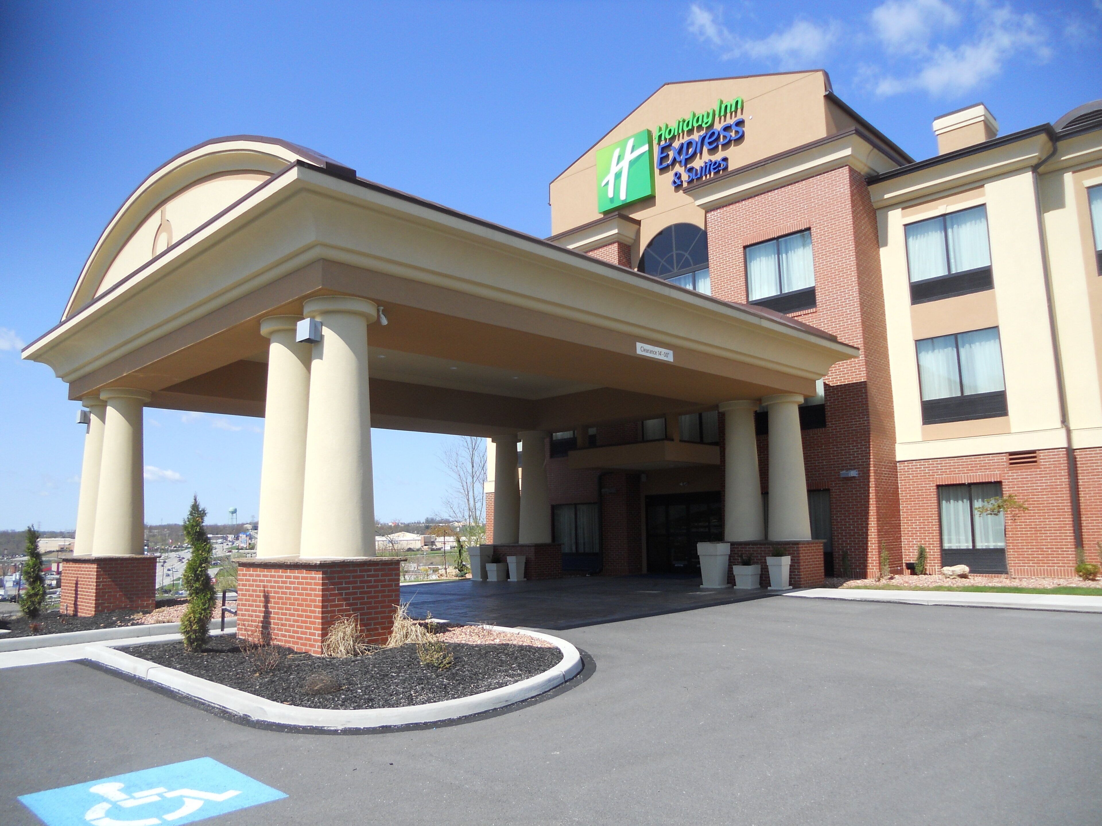 A Holiday Inn Express & Suites with a covered entrance and a handicap parking sign.