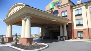 A Holiday Inn Express & Suites with a covered entrance and a handicap parking sign.