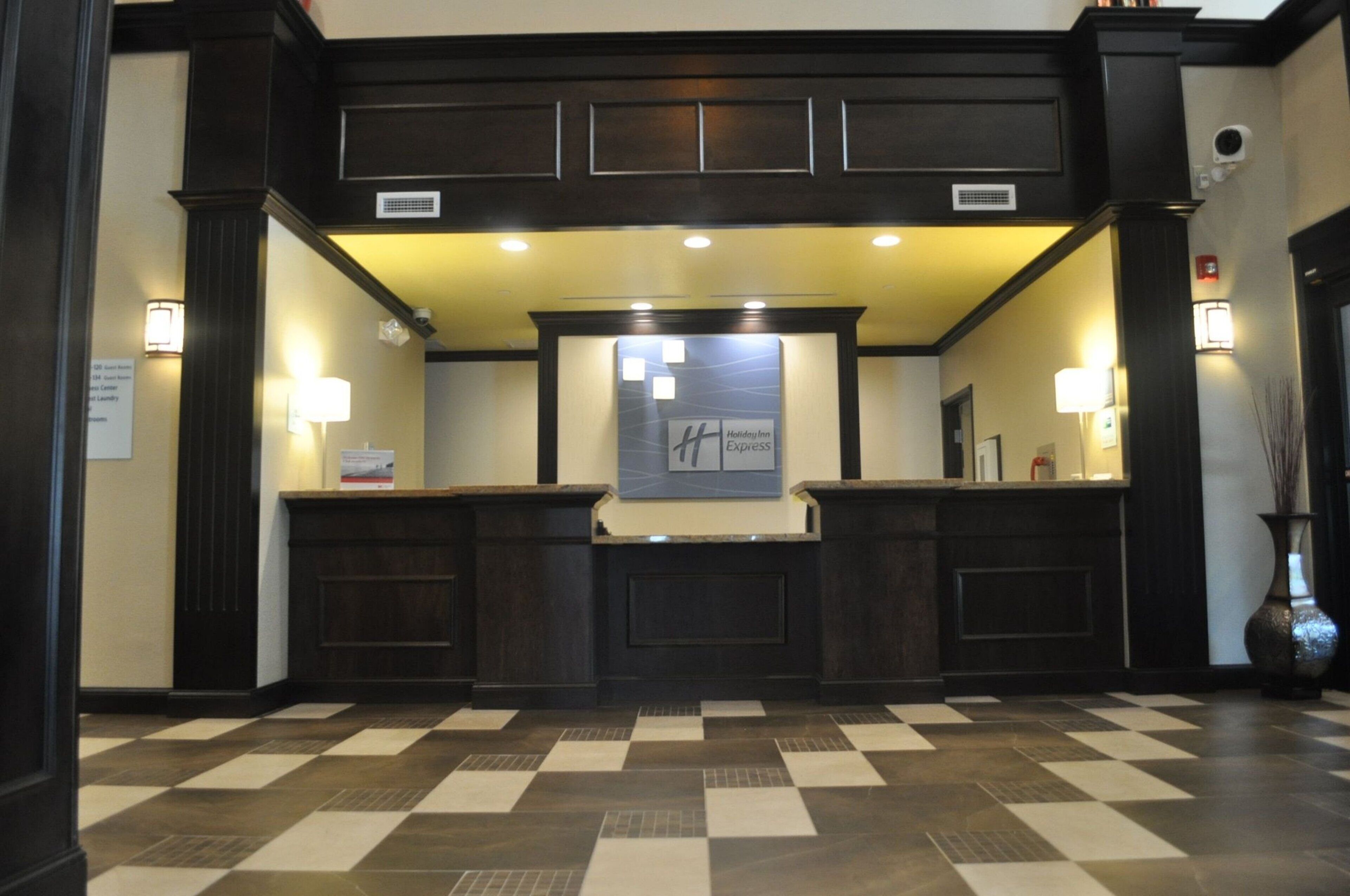 Un área de recepción con piso a cuadros, paneles de madera oscura y un letrero de Holiday Inn Express.
