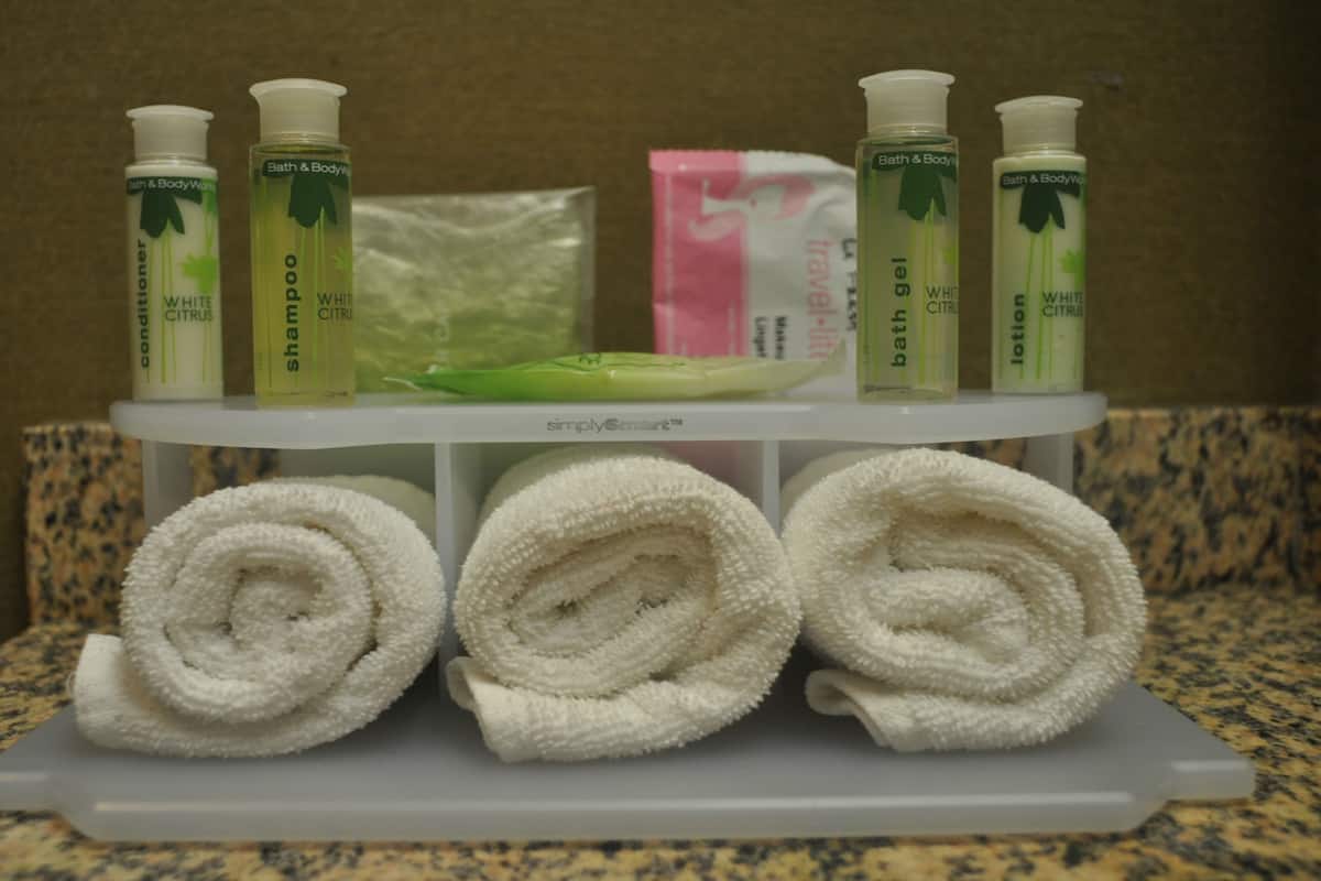 Une étagère de salle de bain avec des articles de toilette et des serviettes.