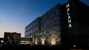 A modern building with the name 'MALANA' illuminated on the facade. - Malana Hotels & Suites (Cotulla)