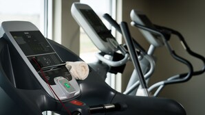 A treadmill with a digital display and a towel placed on the console. - Malana Hotels & Suites (Cotulla)