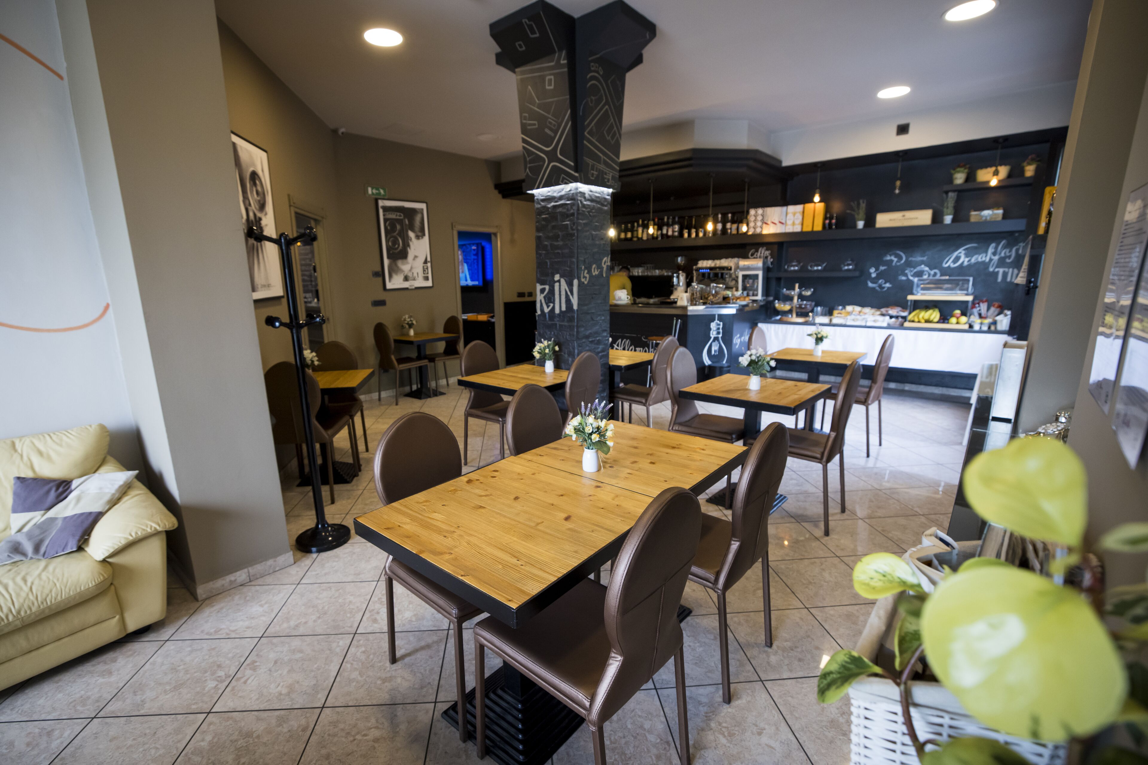 Un restaurant moderne avec des tables et des chaises en bois, un bar et une cuisine visible au fond de la salle.
