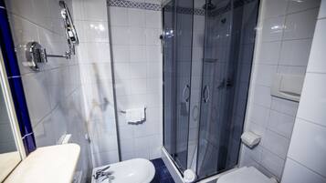 Une salle de bain avec une douche à parois de verre, un lavabo blanc et des toilettes.