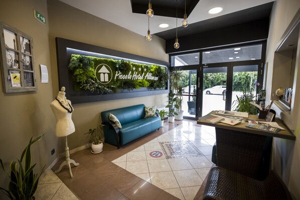 A reception area with a green wall, a blue sofa, a mannequin, and a reception desk.