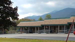 A motel with a green roof and a porch with a railing. - Mountain Brook Lodge (Wilmington)