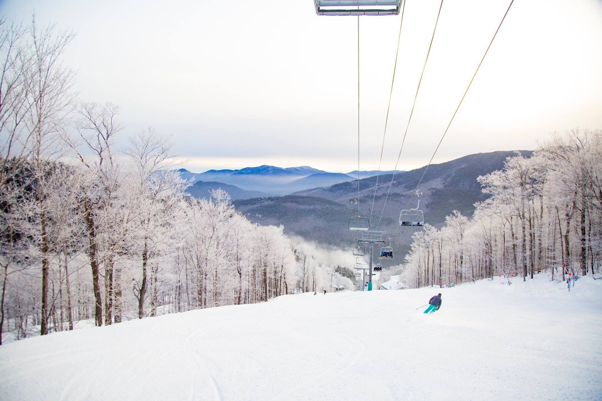 A snowy ski slope with a ski lift and trees.