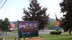 A sign for Mountain Brook Lodge with an American flag and a gift shop sign. - Mountain Brook Lodge (Wilmington)