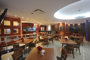 A restaurant with multiple tables and chairs, a staircase, and a stone wall.