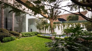 Jardim bem cuidado com diversas plantas e um pequeno lago.