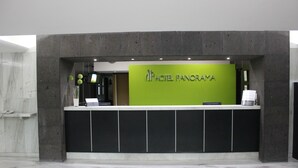 Uma mesa de recepção com uma placa verde que diz "HOTEL PANORAYA" e um balcão preto.