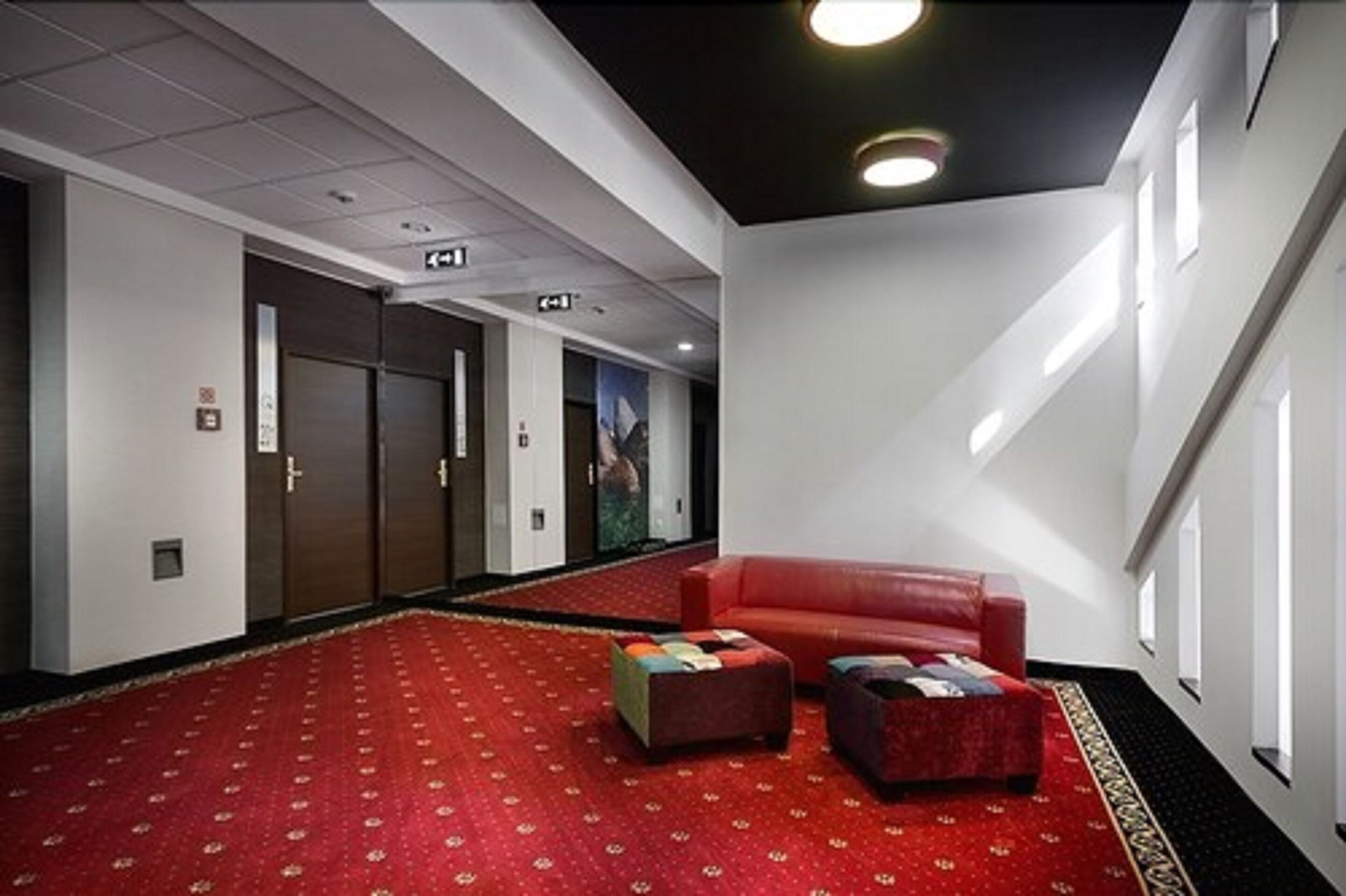 Een hotel lobby met een rood tapijt, een rode bank en een kleine tafel.