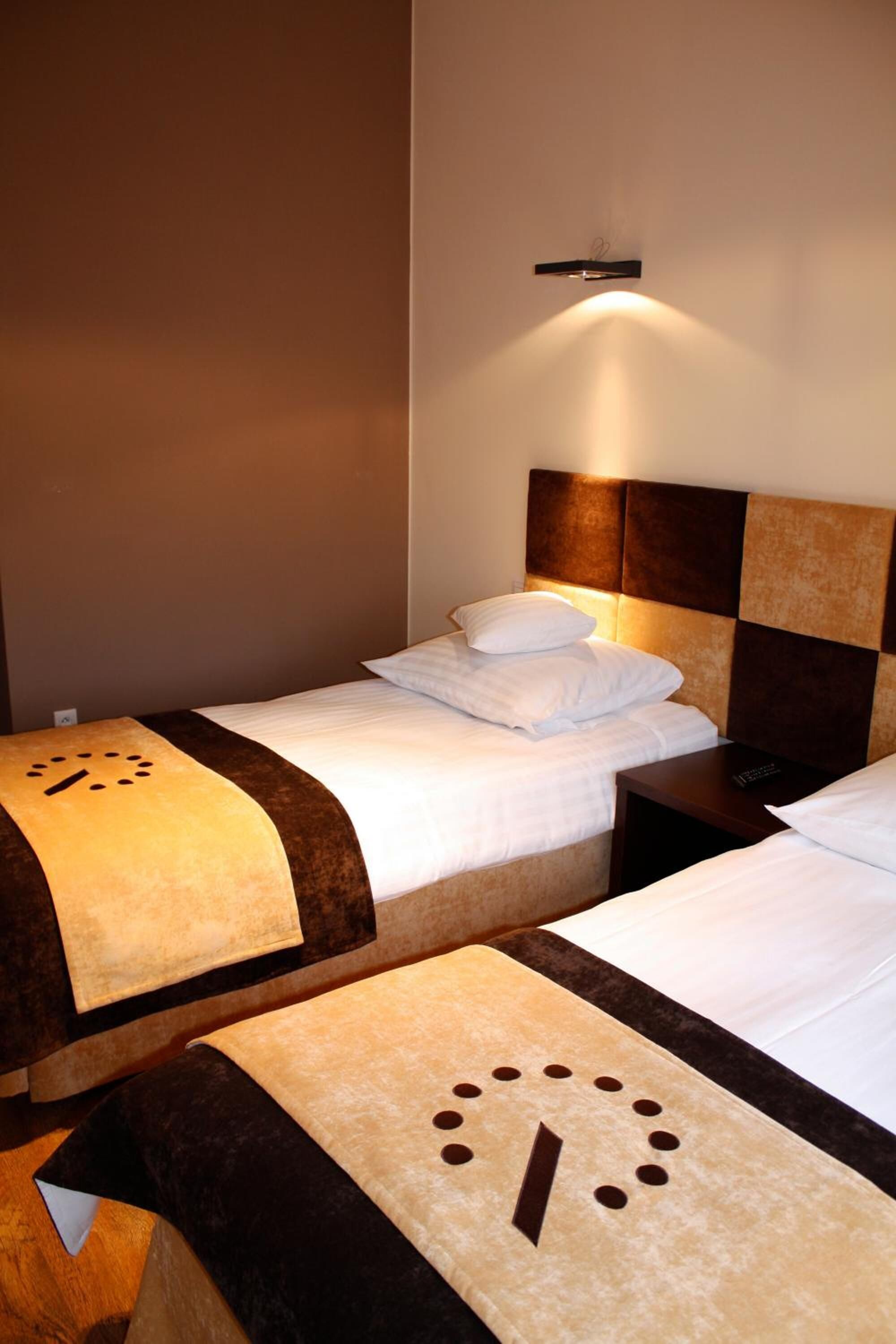 Een hotelkamer met twee bedden, elk met hoofdeind en nachtkastjes.