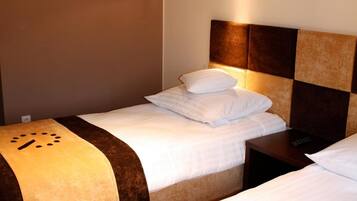 Een hotelkamer met twee bedden, elk met hoofdeind en nachtkastjes.