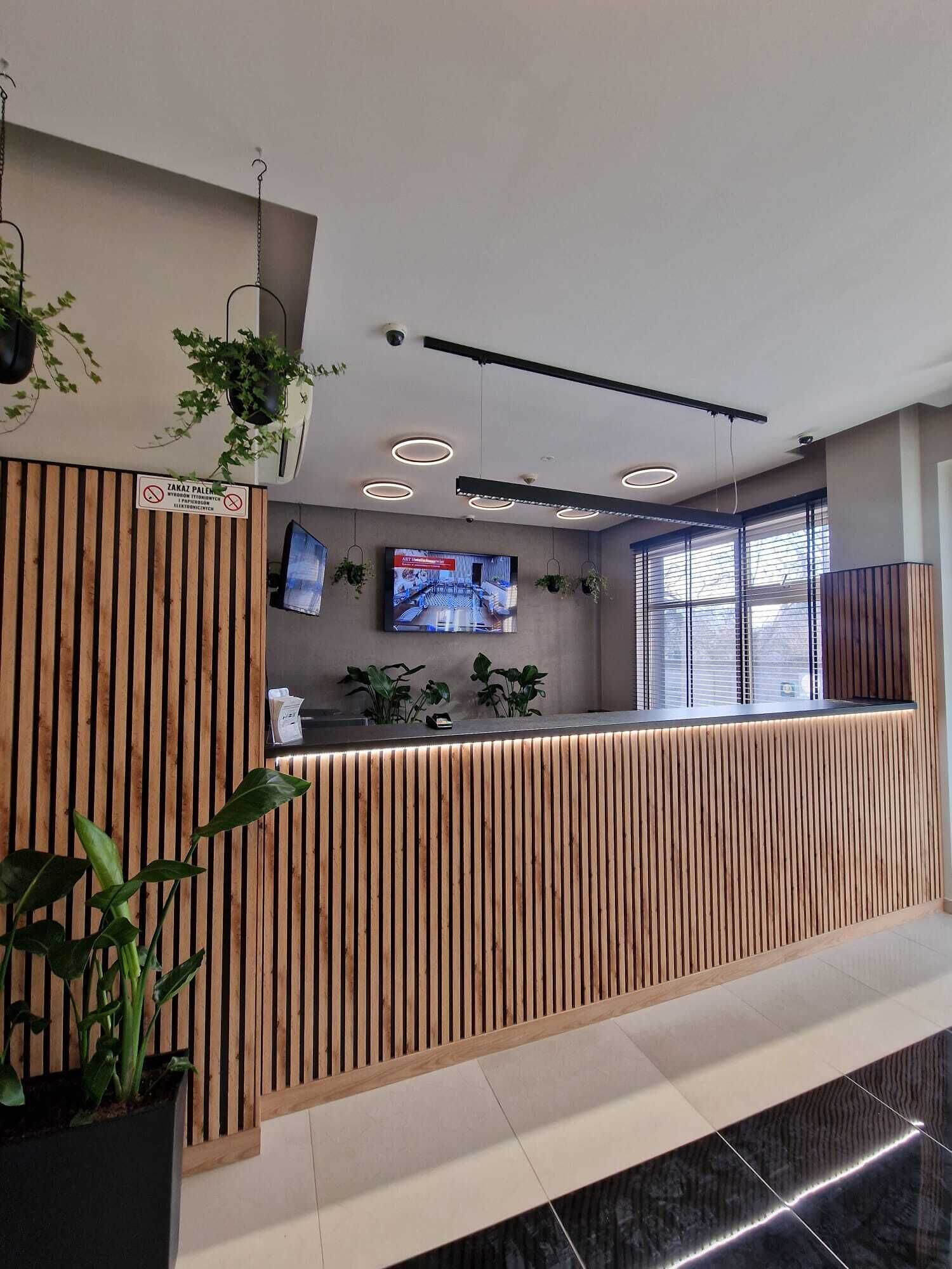 Una recepción con un diseño de listones de madera, un televisor de pantalla plana montado en la pared y plantas en macetas.
