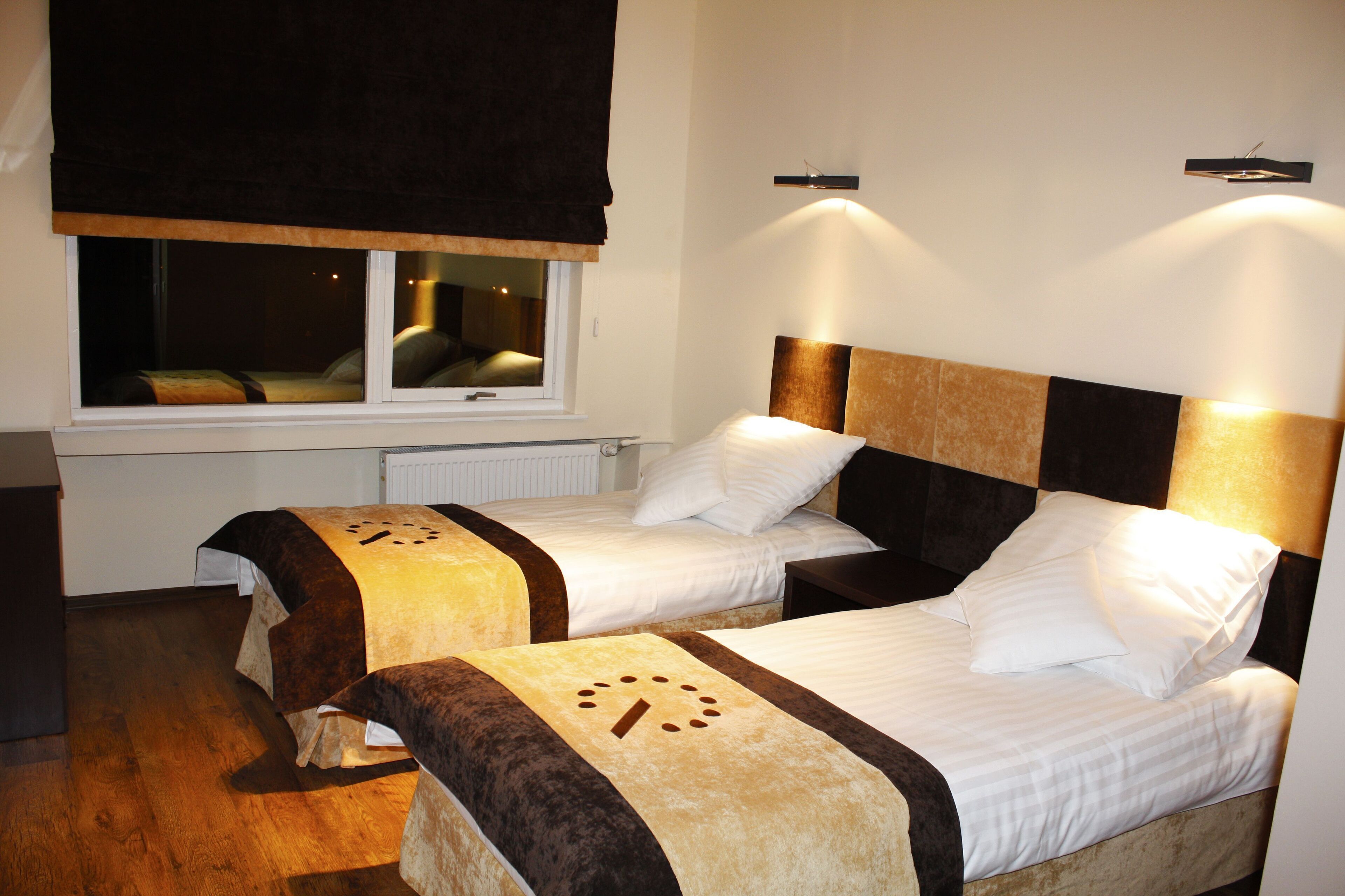 A hotel room with two beds, a window with a view, and a radiator.