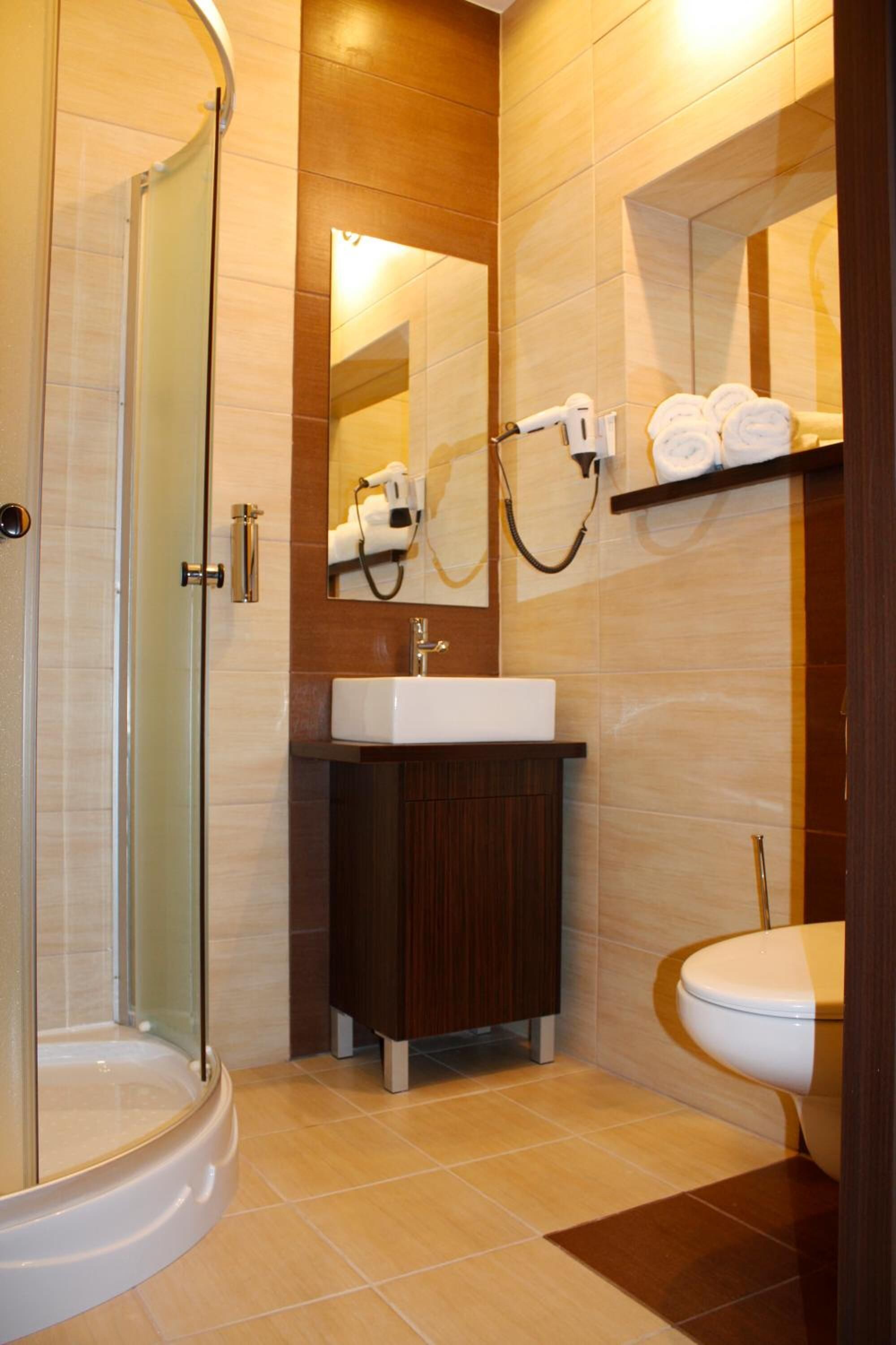 Een moderne badkamer met een douche met glazen wand, een witte wastafel en een toilet.